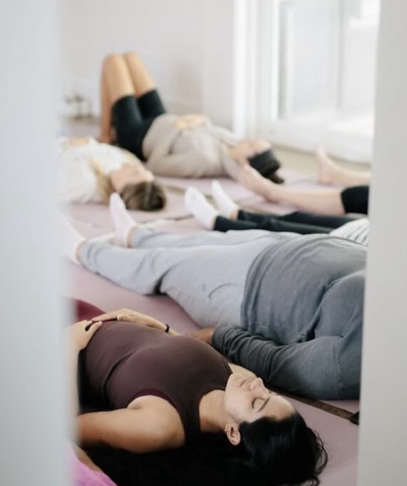 Women resting in savasana during a Kaleo Retreats breathwork session
