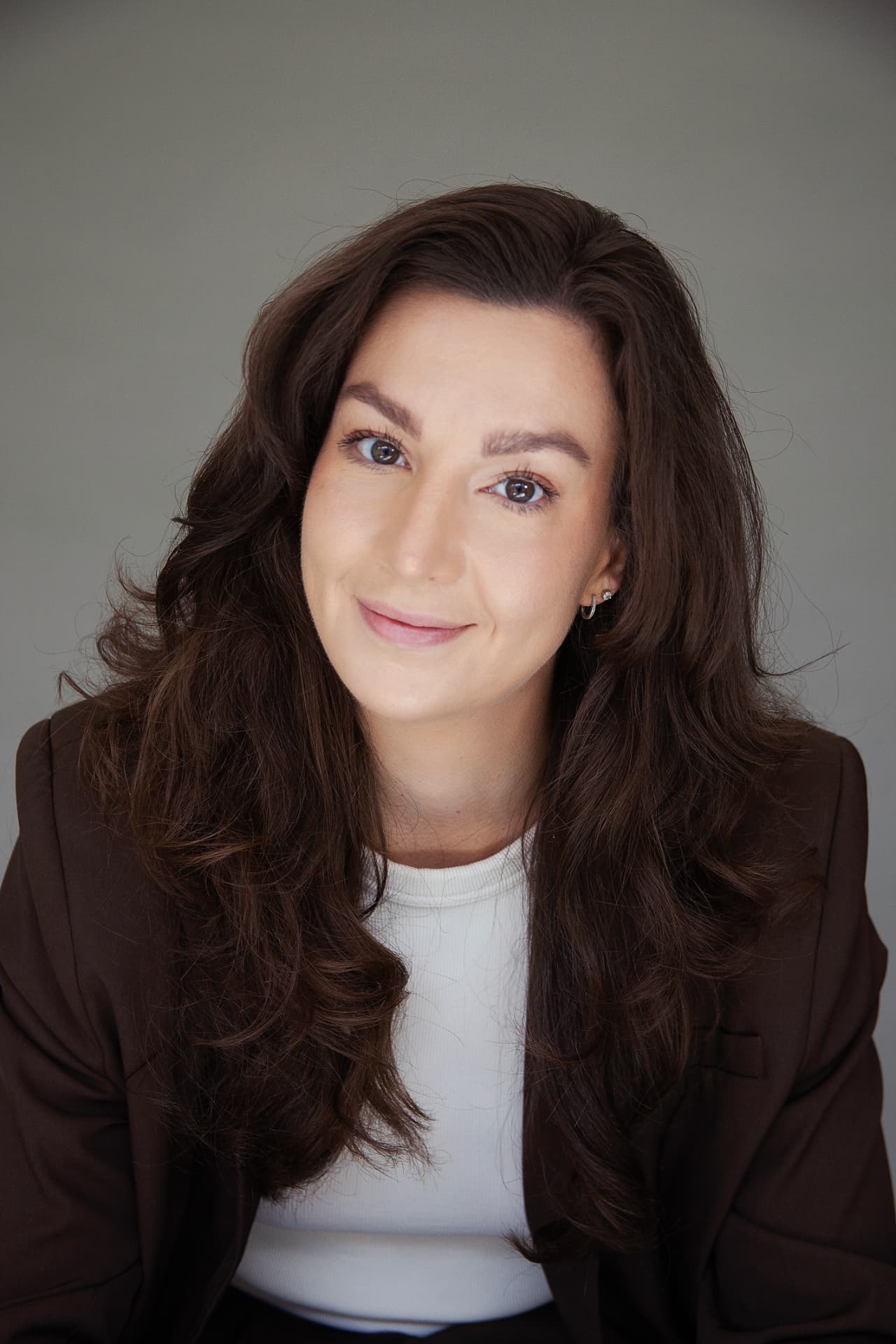 Portrait of Annieck smiling in a brown blazer